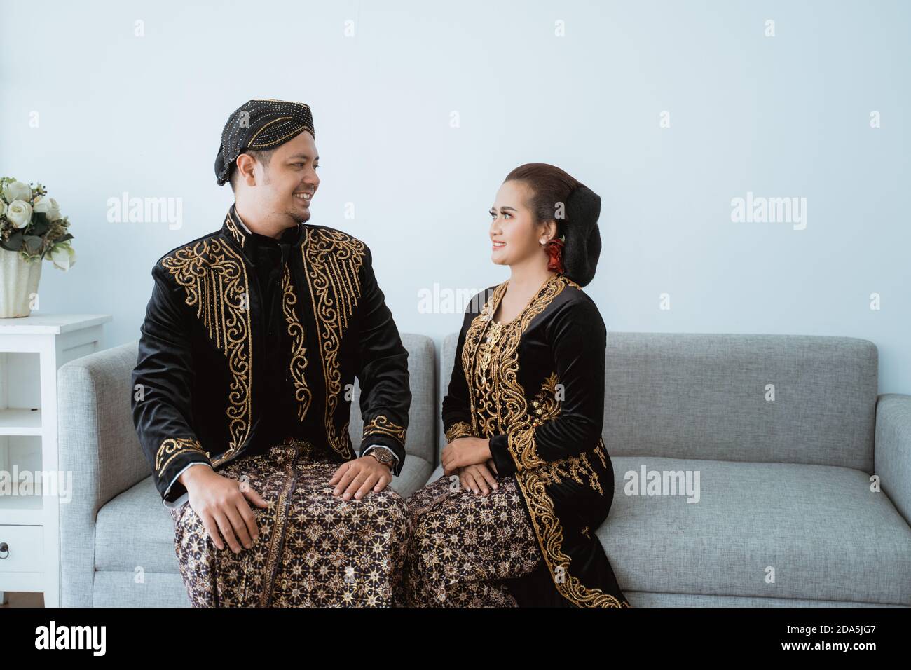 Portrait happy men and women wearing javanese traditional clothes. Couple photo concept in the living room Stock Photo