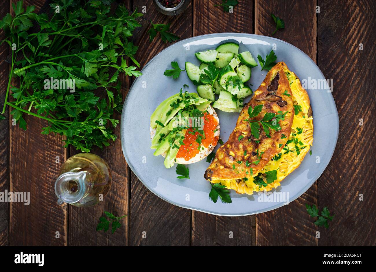 Omelette with forest mushroom, fusilli pasta and sandwich wich red caviar, avocado on plate.  Frittata - italian omelet. Top view, overhead, copy spac Stock Photo