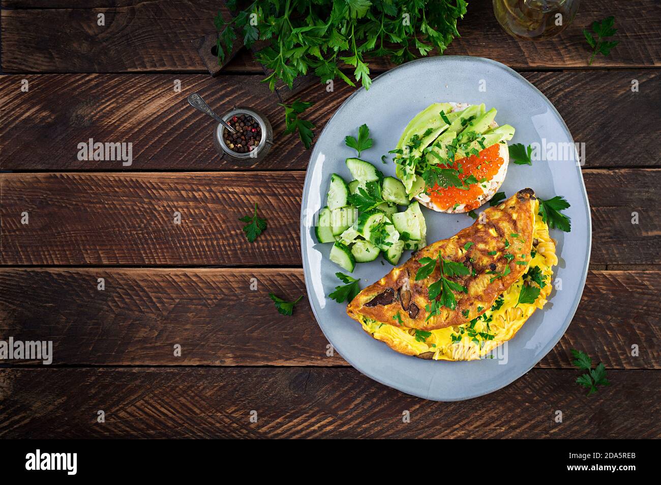 Omelette with forest mushroom, fusilli pasta and sandwich wich red cavier, avocado on plate.  Frittata - italian omelet. Top view, overhead, copy spac Stock Photo