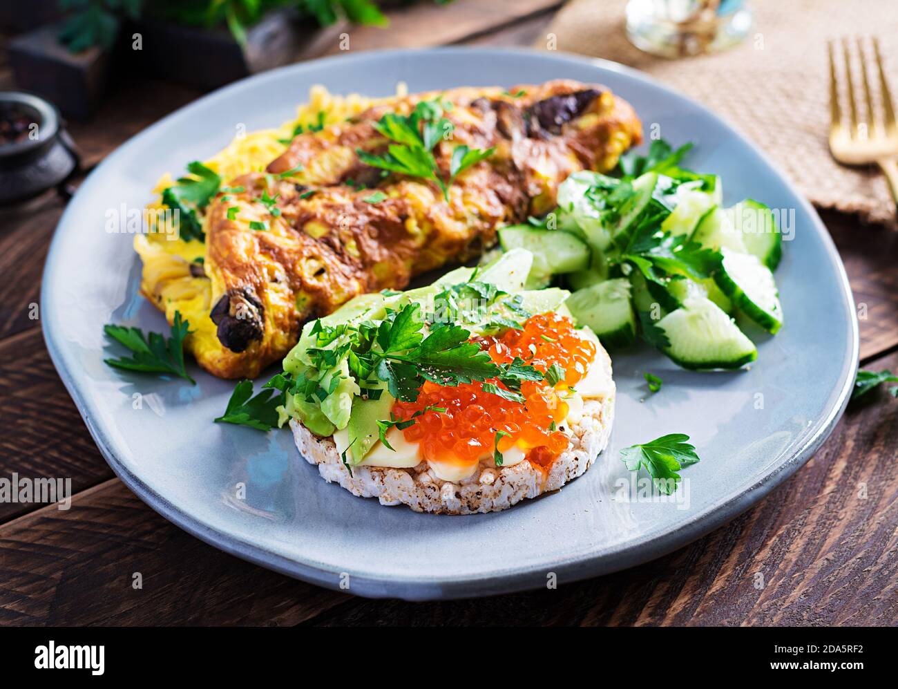 Omelette with forest mushroom, fusilli pasta and sandwich wich red caviar, avocado on plate.  Frittata - italian omelet. Stock Photo