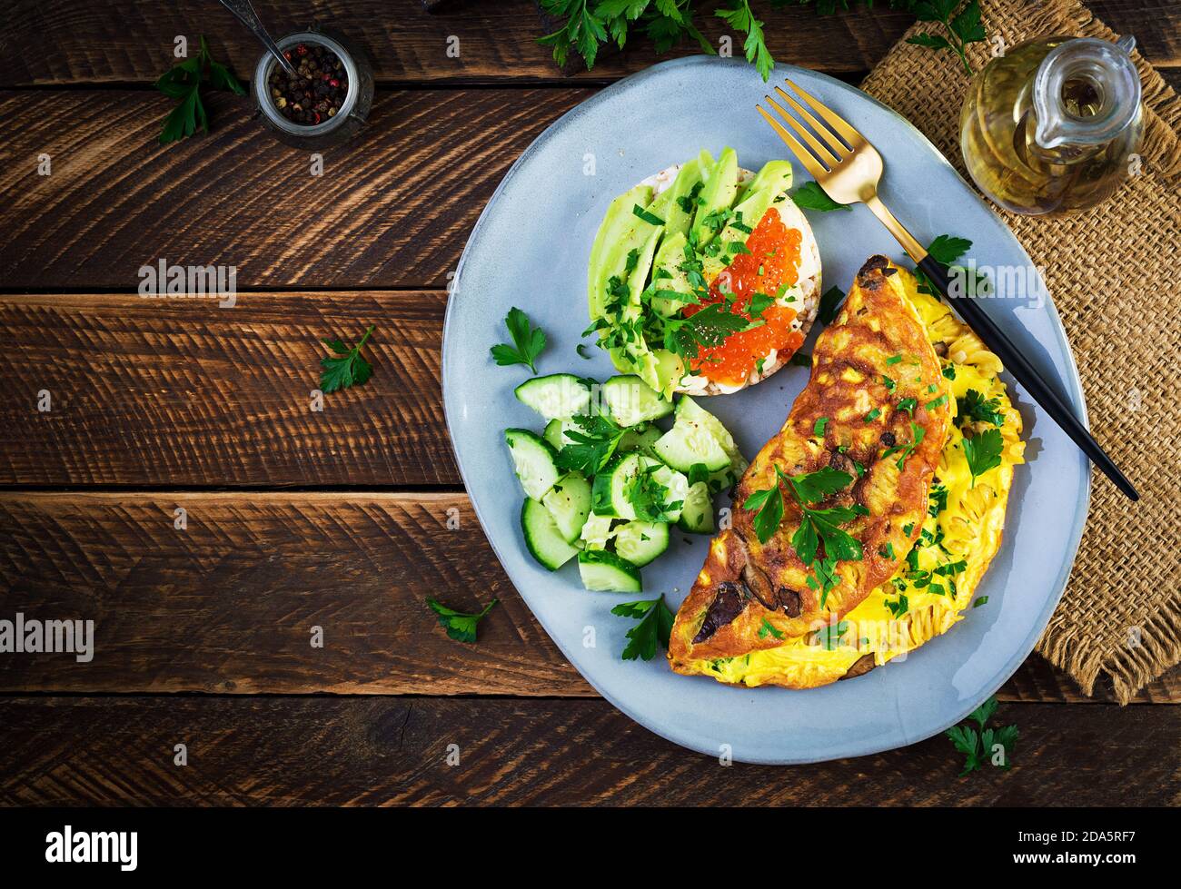 Omelette with forest mushroom, fusilli pasta and sandwich wich red caviar, avocado on plate.  Frittata - italian omelet. Top view, overhead, copy spac Stock Photo