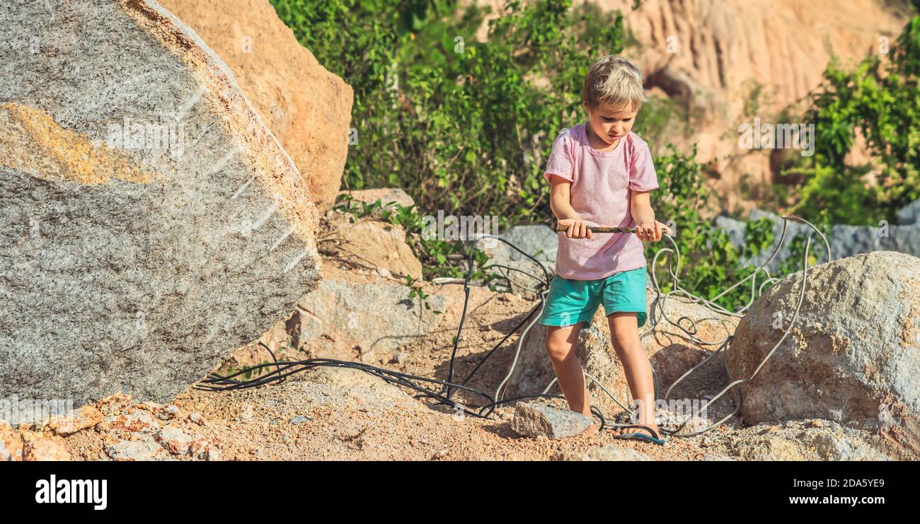 Serious Boy find play metal corrugated steel reinforcement, hold in open palm hand, wires ropes. Children safety near construction sites waste Stock Photo