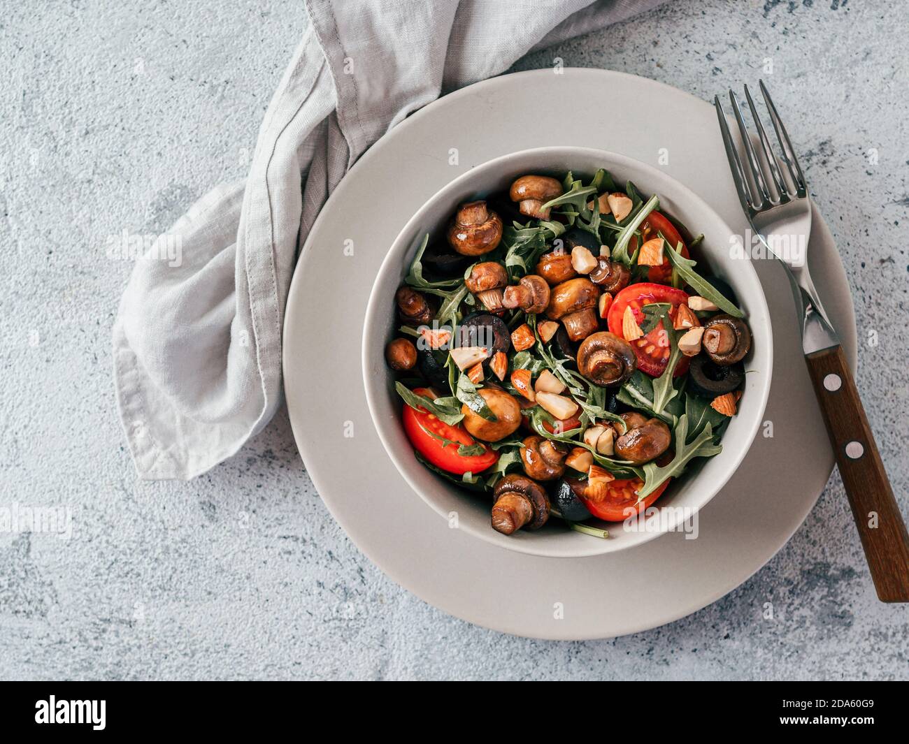 Salad with arugula, mini champignons, cherry tomatoes, black olives, pine nuts. Vegetarian salad top view or flat lay. Copy space. Horizontal Stock Photo