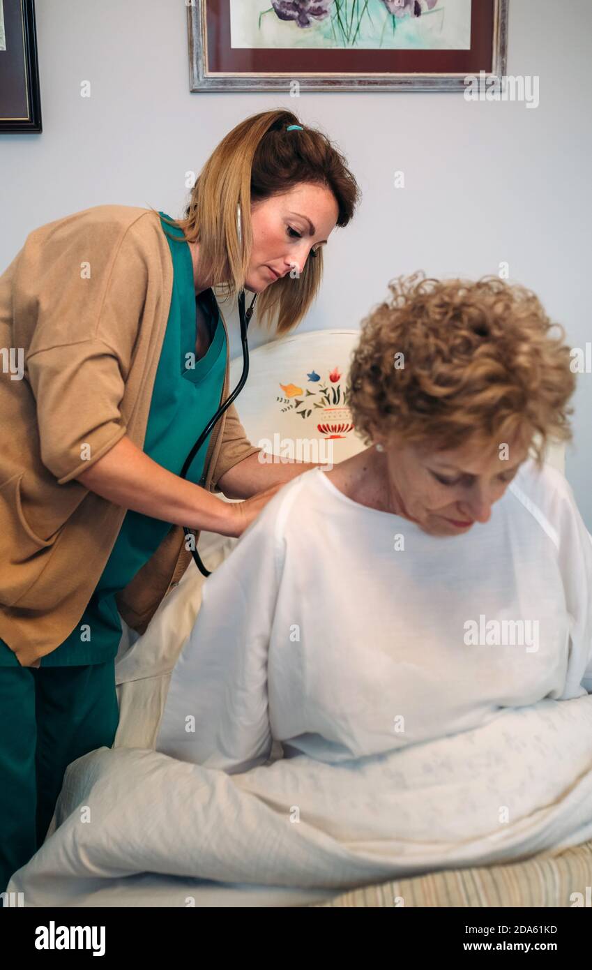 Caregiver auscultating senior woman Stock Photo