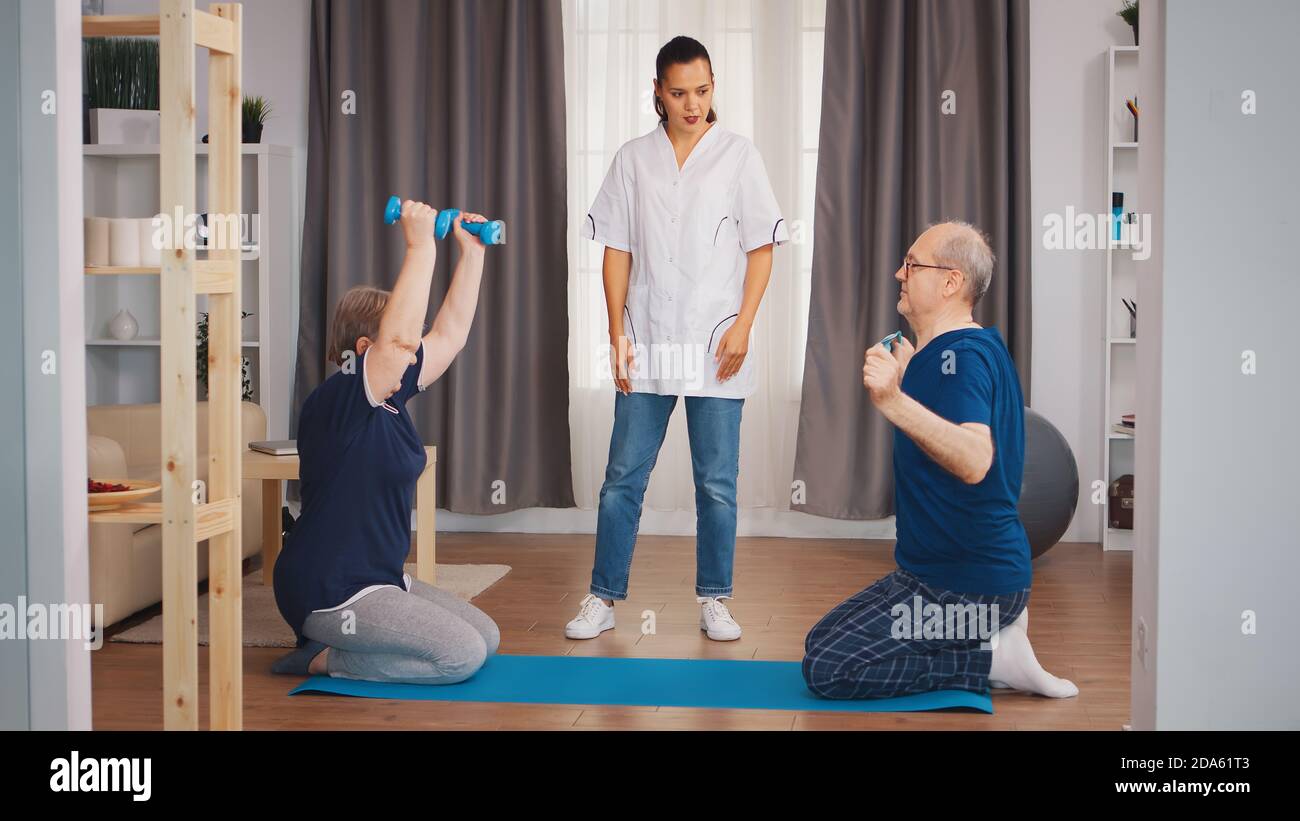 Old couple exercise with nurse during their body rehabilitation. Home ...