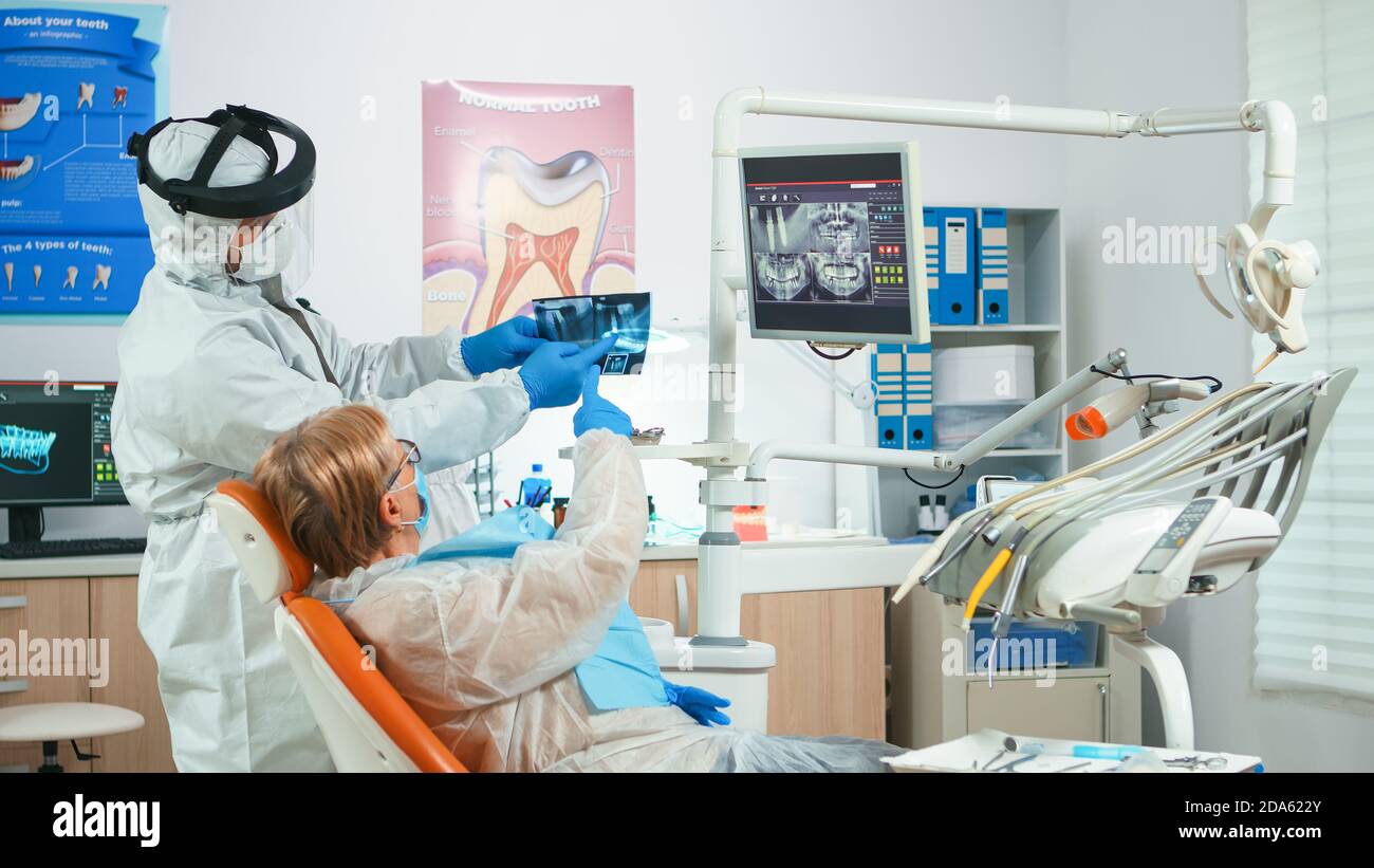 Dentist with face shield reviewing panoramic mouth xray image to