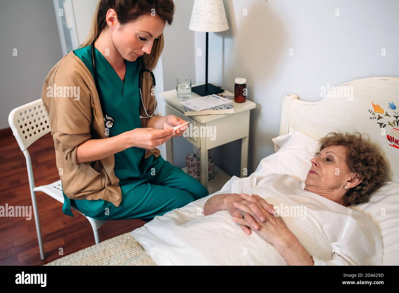 Doctor taking temperature to senior woman Stock Photo