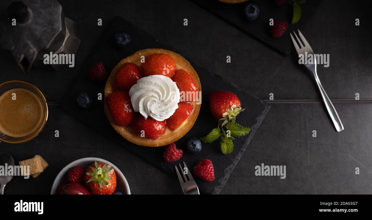Homemade organic strawberry pie with raspberry and blue berry with a coffee on a dark background top view. Stock Photo