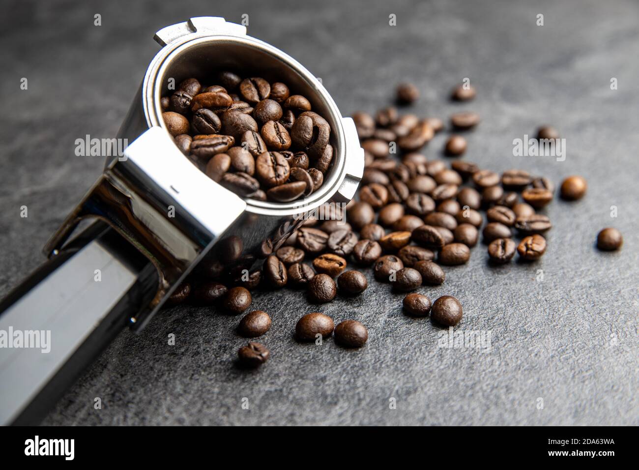 Roasted coffee beans in coffee filter holder on black table. Stock Photo