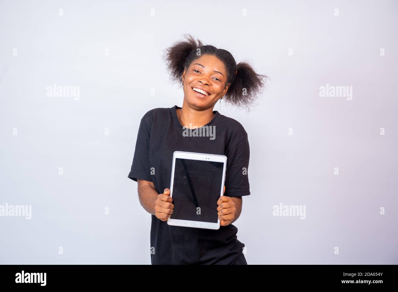 happy young african lady holding a tablet computer with the screen facing forward Stock Photo