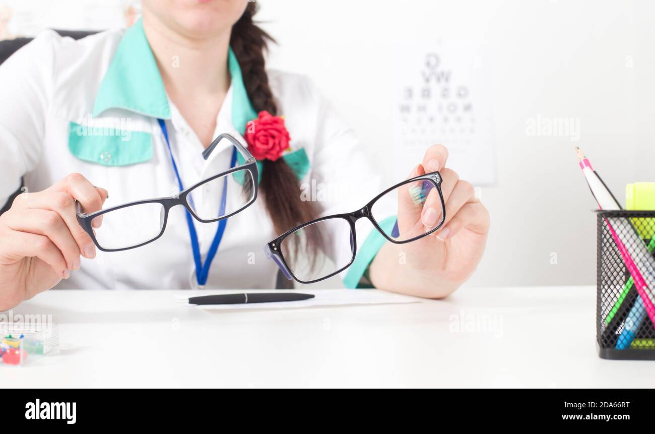 Doctor ophthalmologist holds in his hands two glasses for the eyes. The concept of choosing the right and comfortable modern glasses Stock Photo
