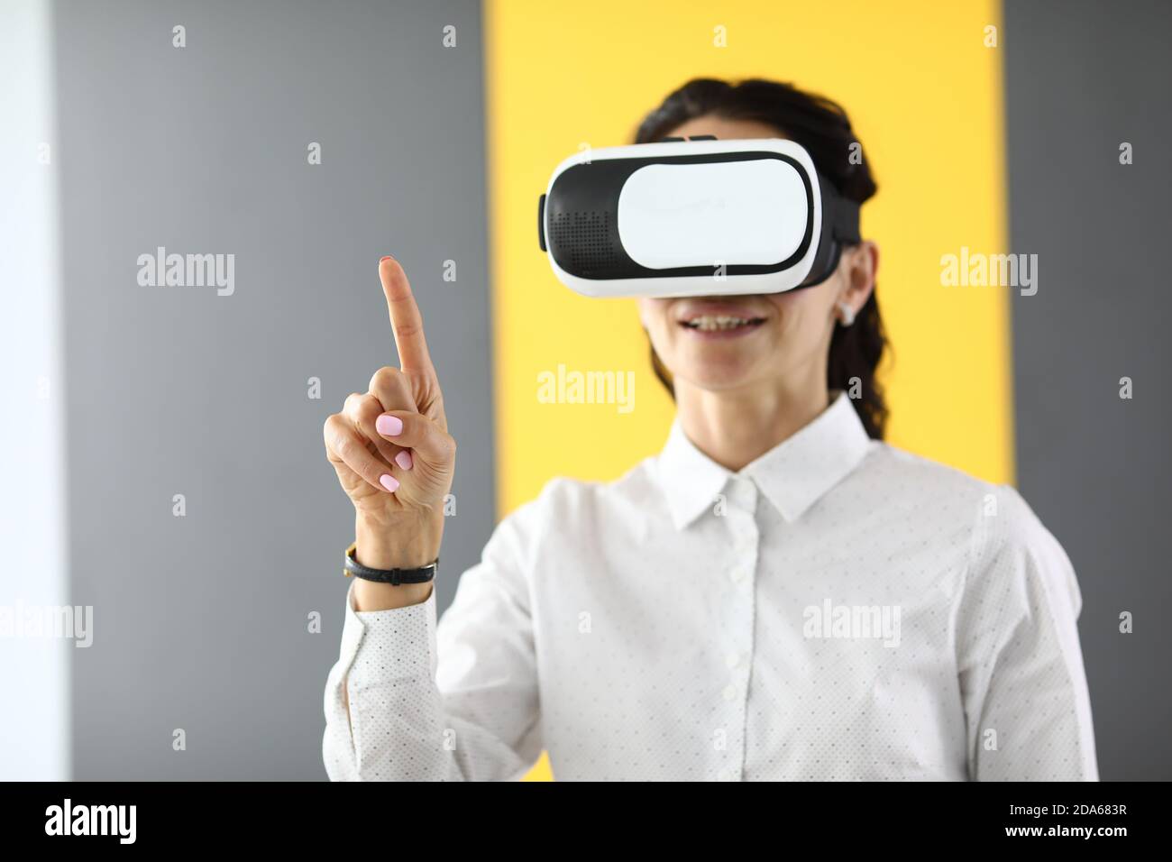 Woman in virtual reality glasses stands and holds her thumbs up. Stock Photo