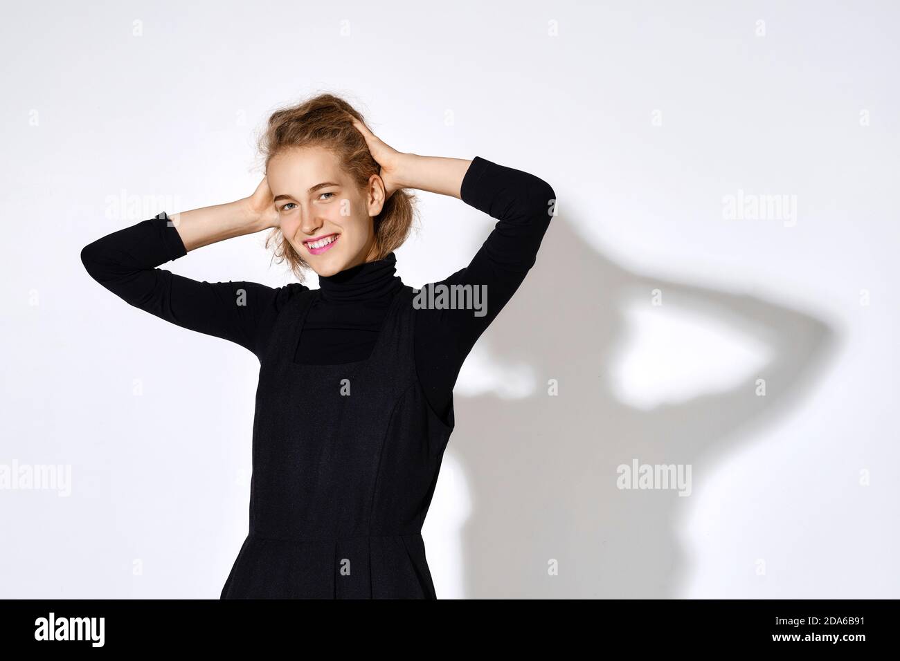 Cute young woman in black pullover holds head with her hands Stock Photo