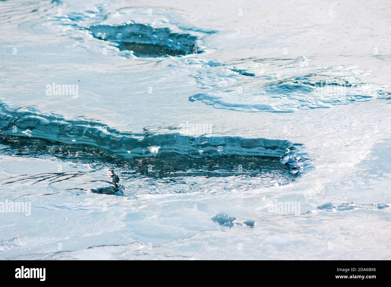 ice texture on the river. close up background. blue color in day light. water flow among cracks Stock Photo