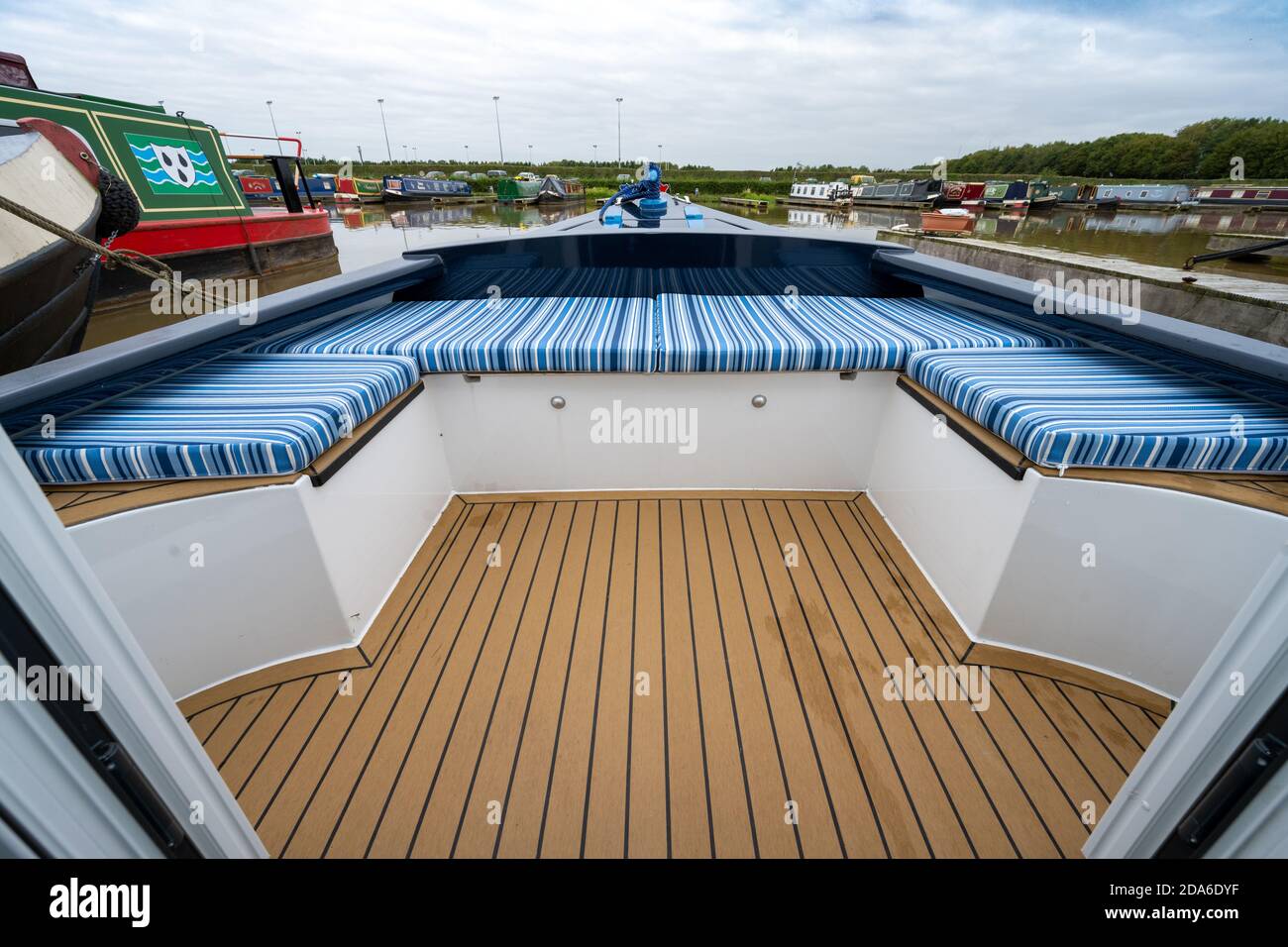 Low angle view of the impressive seating area, upholstered in blue striped material, at the bow of a new narrowboat moored in a marina in the UK Stock Photo