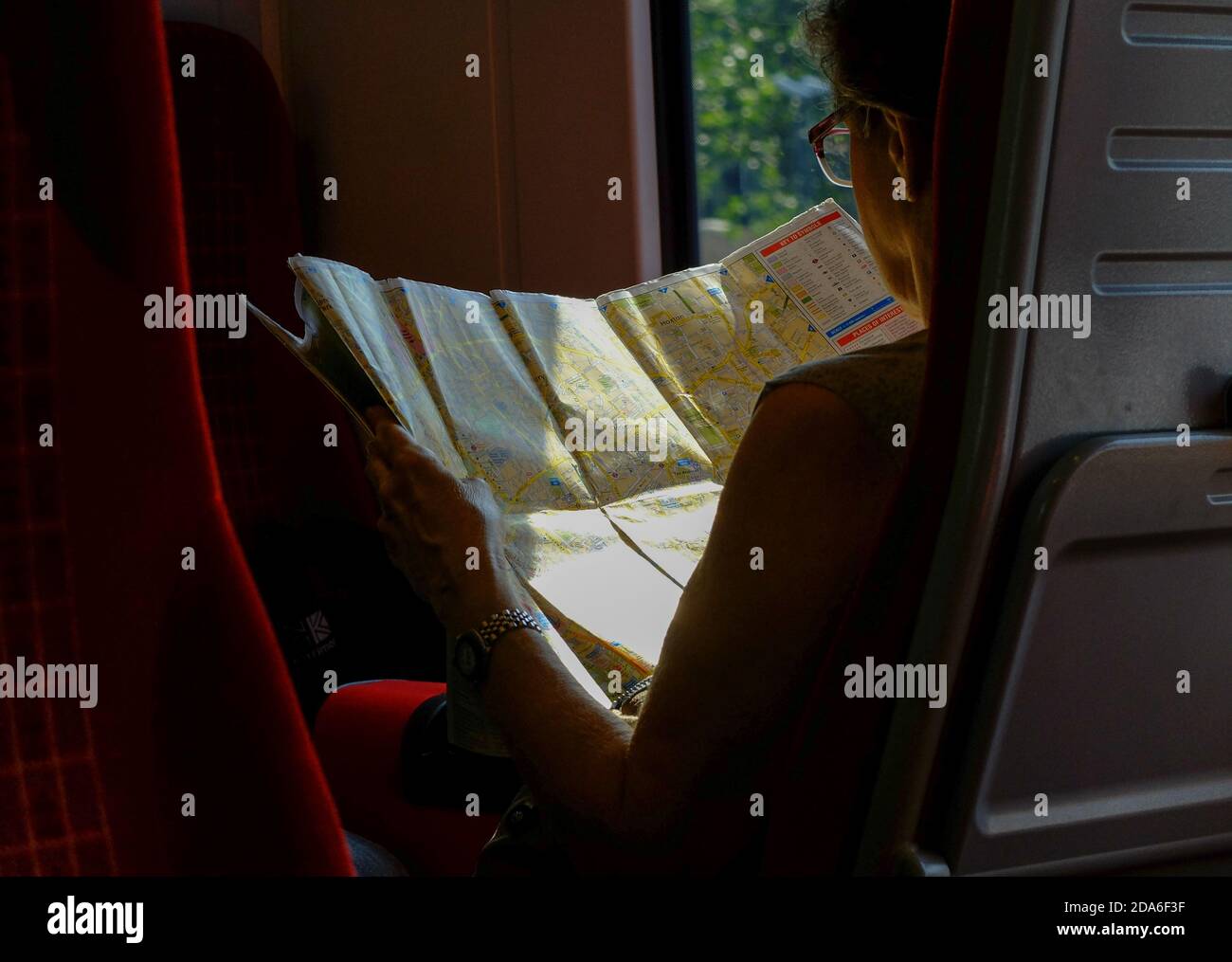 A passenger on a train between Poole and London Waterloo reads a large A to Z tourist map of central London featuring Clerkenwell and Hoxton during the two hour commuter journey from Dorset via Bournemouth and Southamptoonb to the capital city of the United Kingdom. 23 July 2014. Photo: Neil Turner Stock Photo