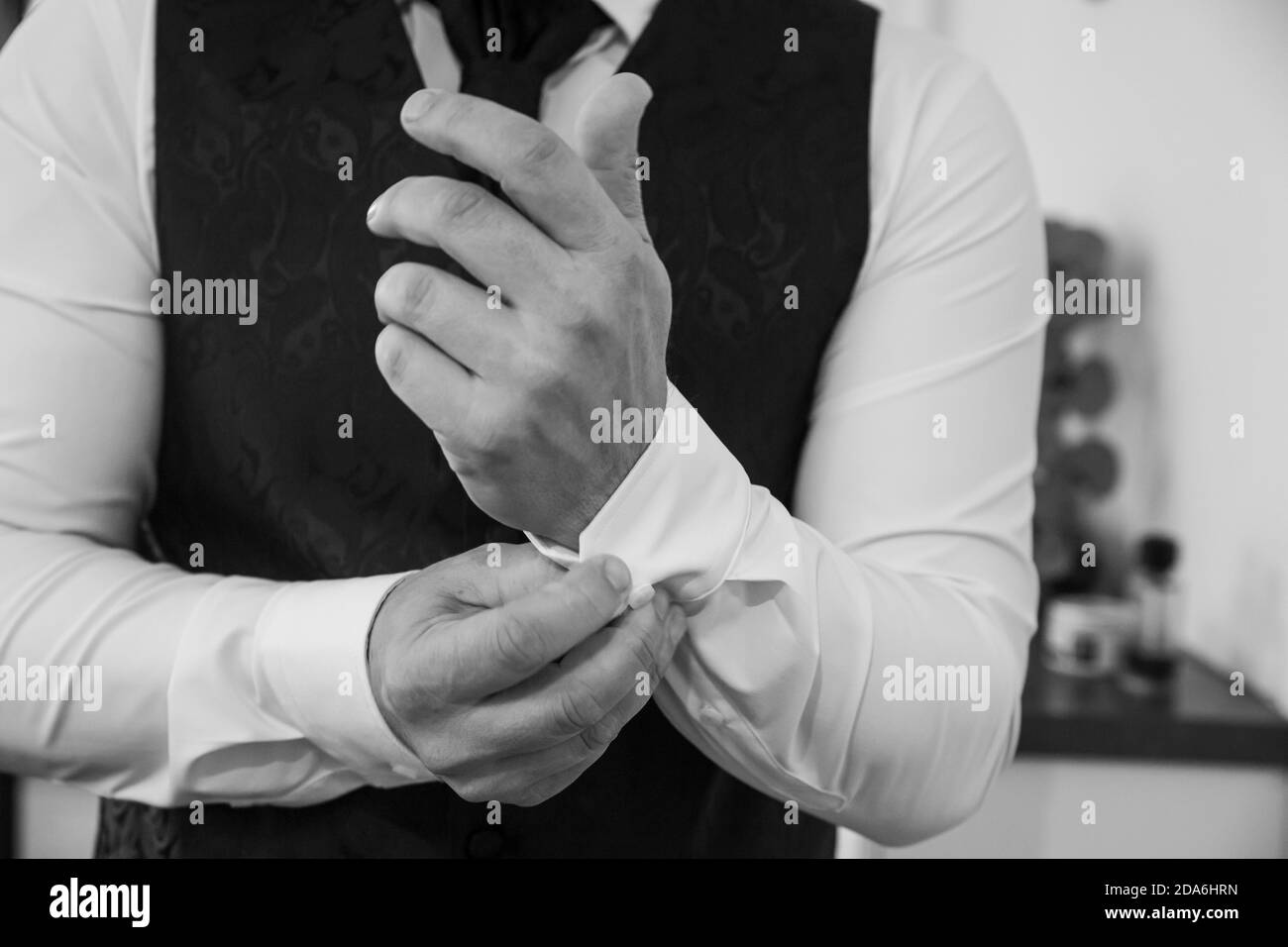 A close up of a groom's hands closing the buttons on his shirt Stock Photo