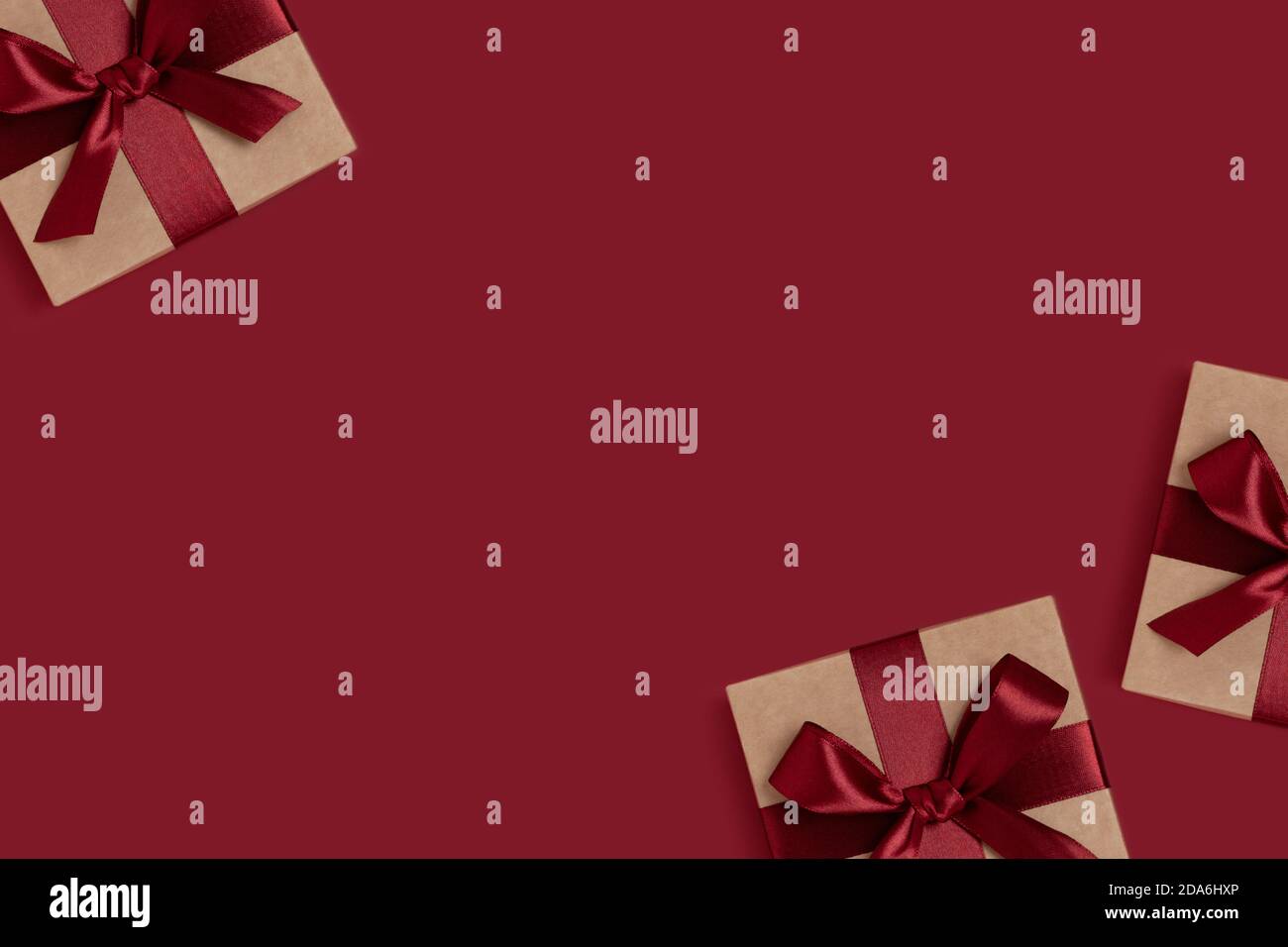 Frame made of gift boxes tied with ribbons on a red background with copy space. New Years composition. Stock Photo