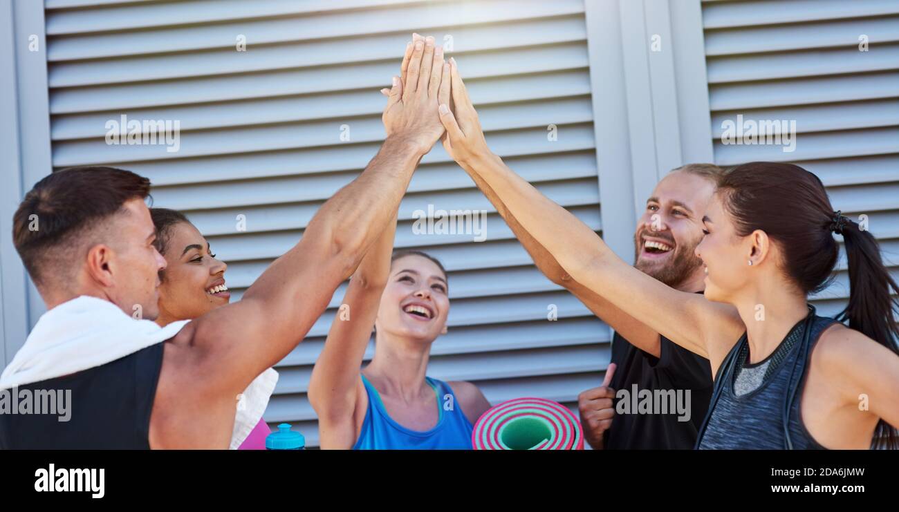 Happy mixed race sport team giving high five near wall Stock Photo - Alamy