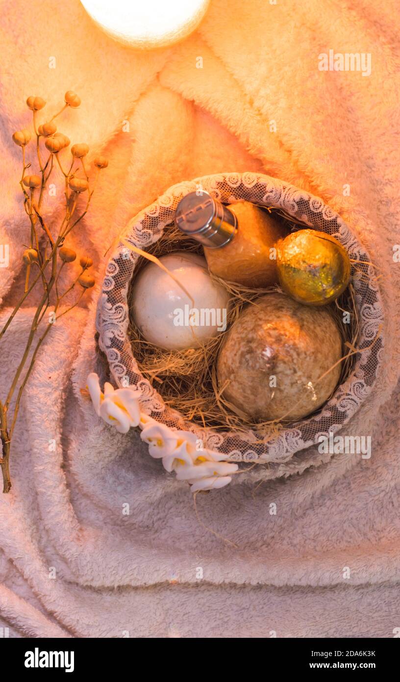 flat lay of a knitted basket with egg-shaped soaps and bath salt in the hay. Bird's nest with gifts for a holiday. Stock Photo