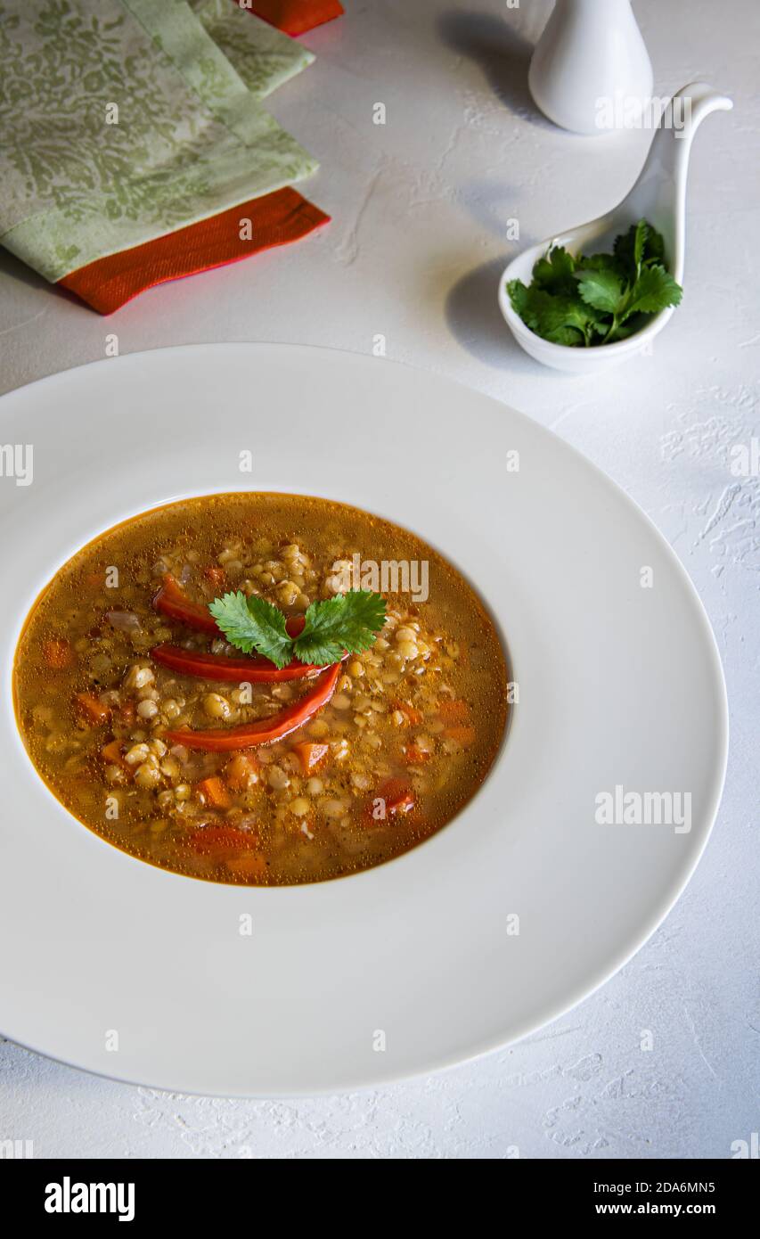 Traditional Bulgarian lentil soup, called leshta chorba in white soup plate. Vegetable stew for vegan and vegetarian menu. Fresh herbs, textile napkin Stock Photo