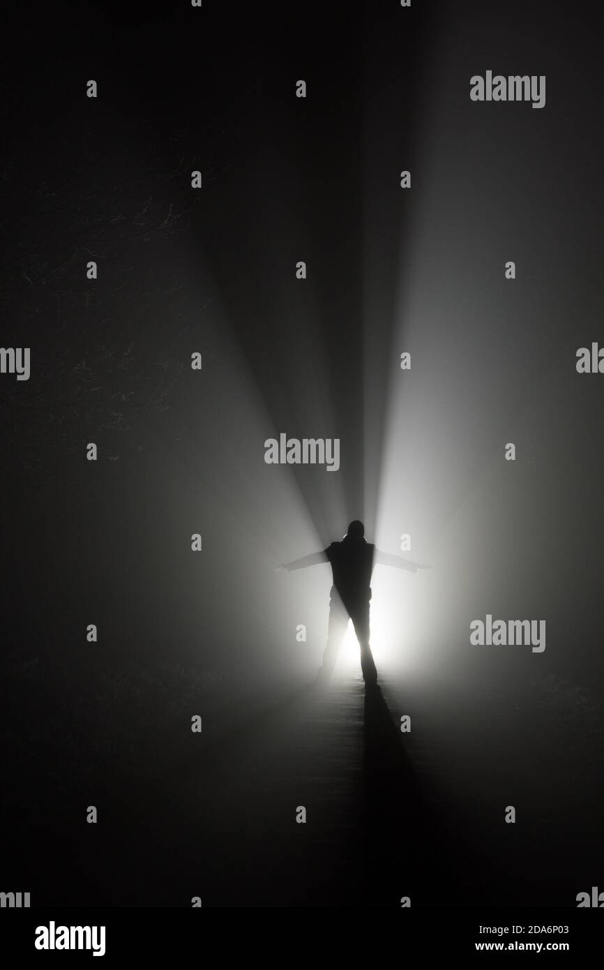 Silhouette of a man, in the rays of light at foggy night Stock Photo ...