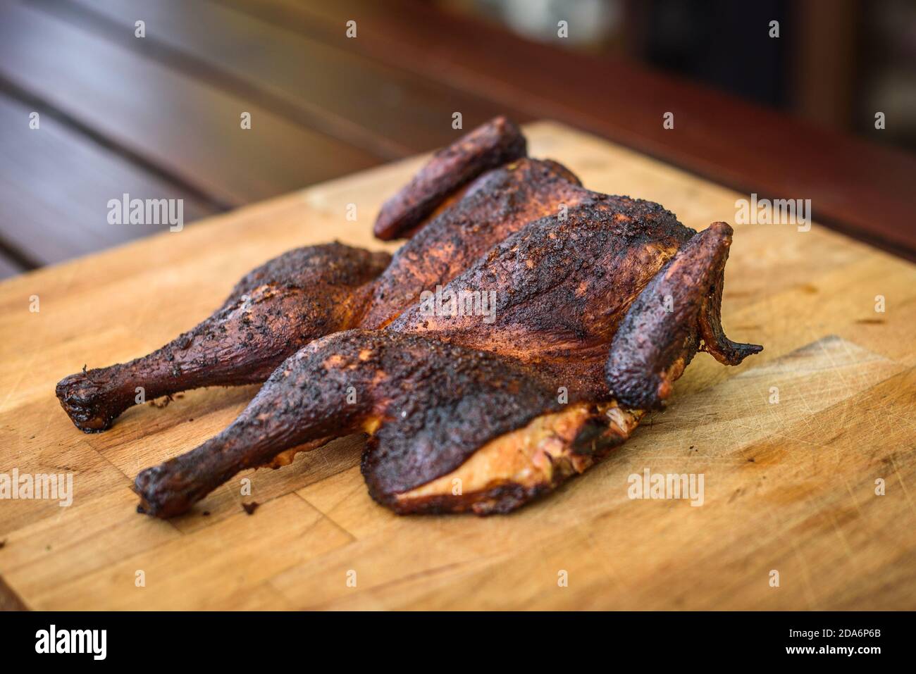 Traditional spatchcocked barbecue chicken al mattone on charcoal grill. Grilling and smoking spatchcock chicken on firewood BBQ grill in nature on fam Stock Photo