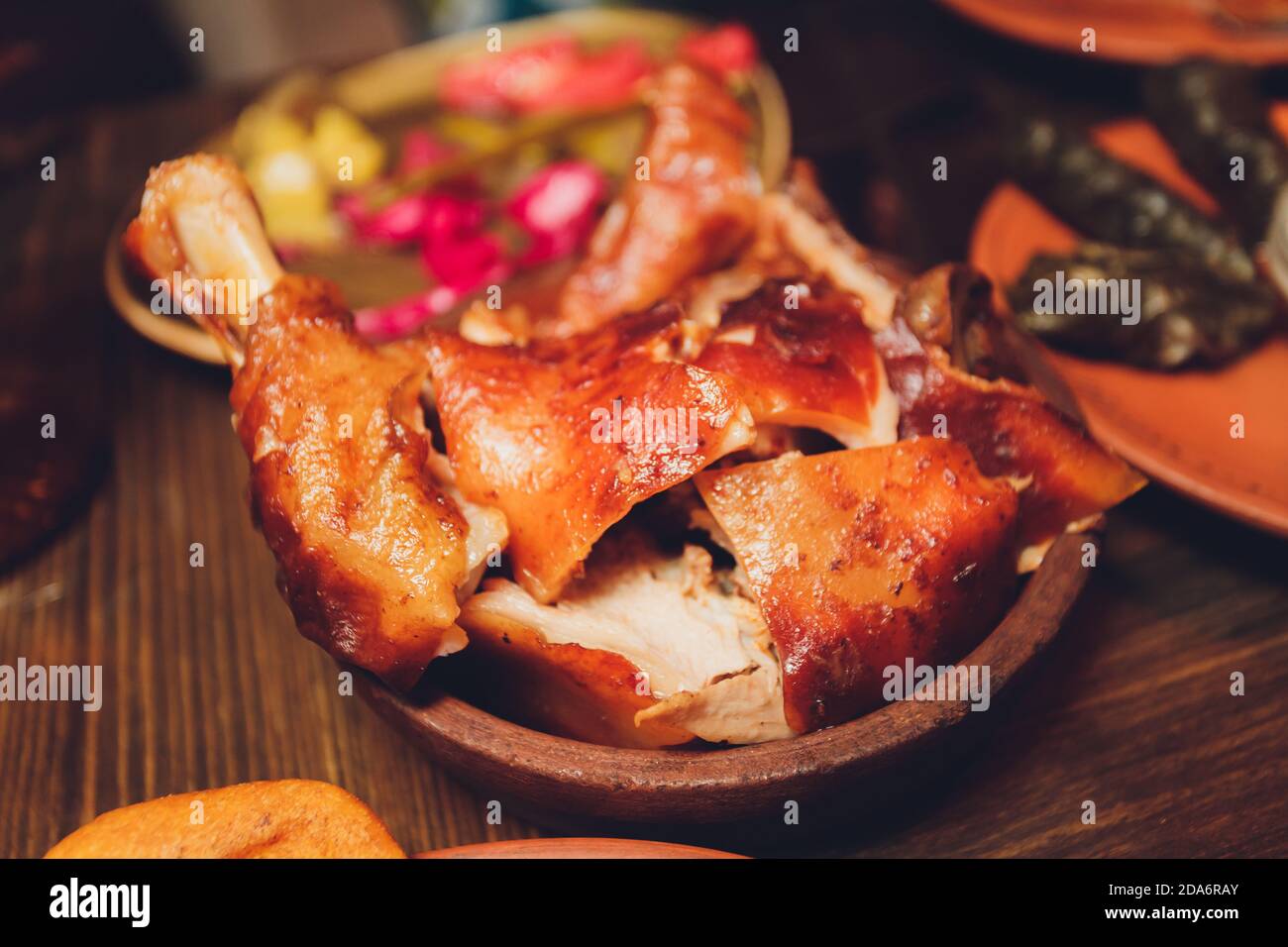 Pork knuckle on wooden surface. Horisontal pork knuckle on round wooden table with side dish