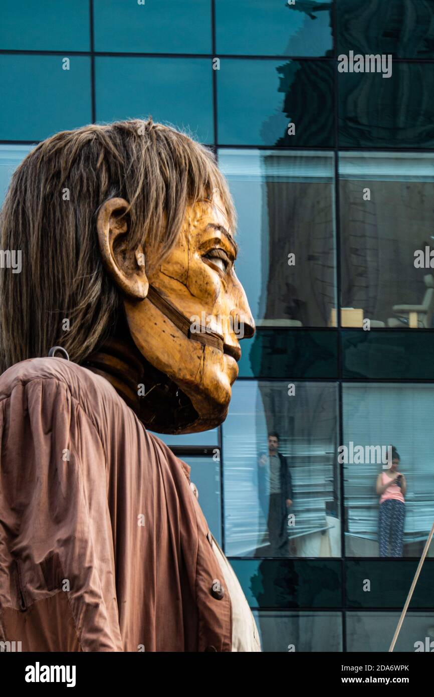 Office workers spectate from their windows as Royal De Luxe's Big Giant puppet makes his progress through the streets of Liverpool, England Stock Photo