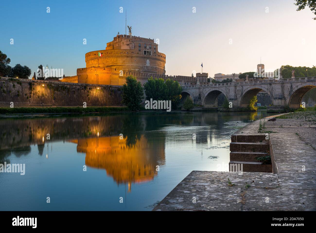 Night to sunrise long exposure of Castel Sant’Angelo (Castle of the Holy Angel), an ancient tomb and fortress, illuminated at night and reflecting on Stock Photo