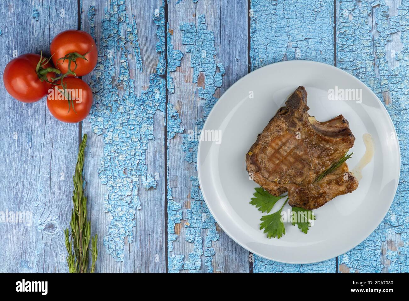 piece of delicious pork. fried steak in a plate on a wooden background. piece of deep-fried meat with tomatoes and a sprig of rosemary.  Stock Photo