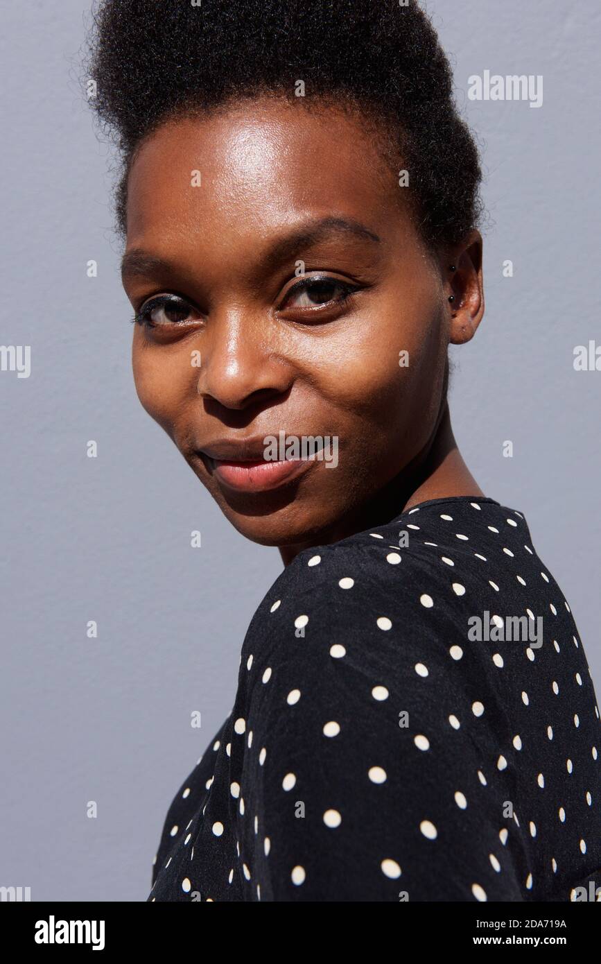 Close up portrait of beautiful young black woman against gray ...