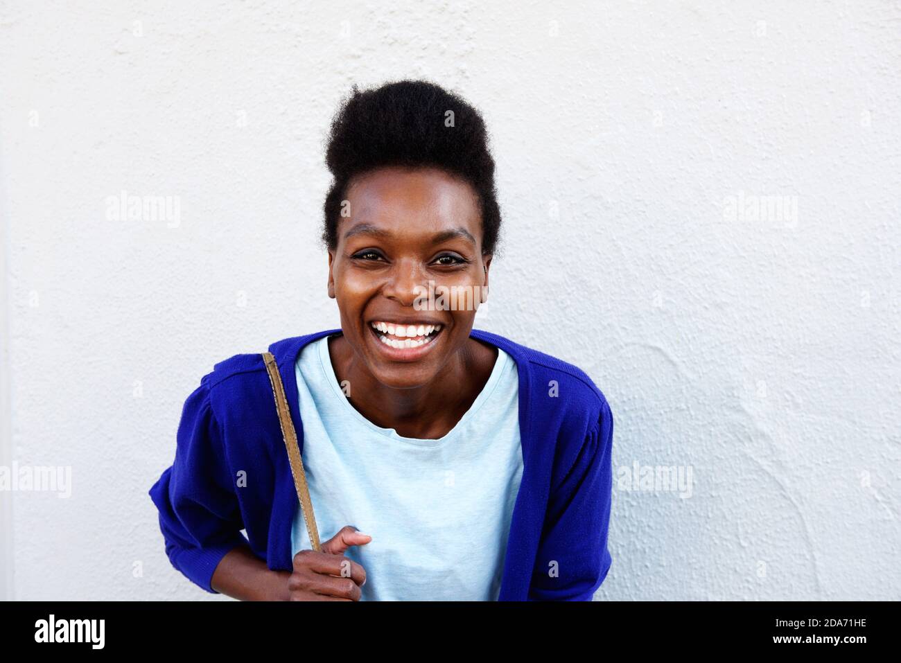 Close up portrait of young african female smiling against white wall ...