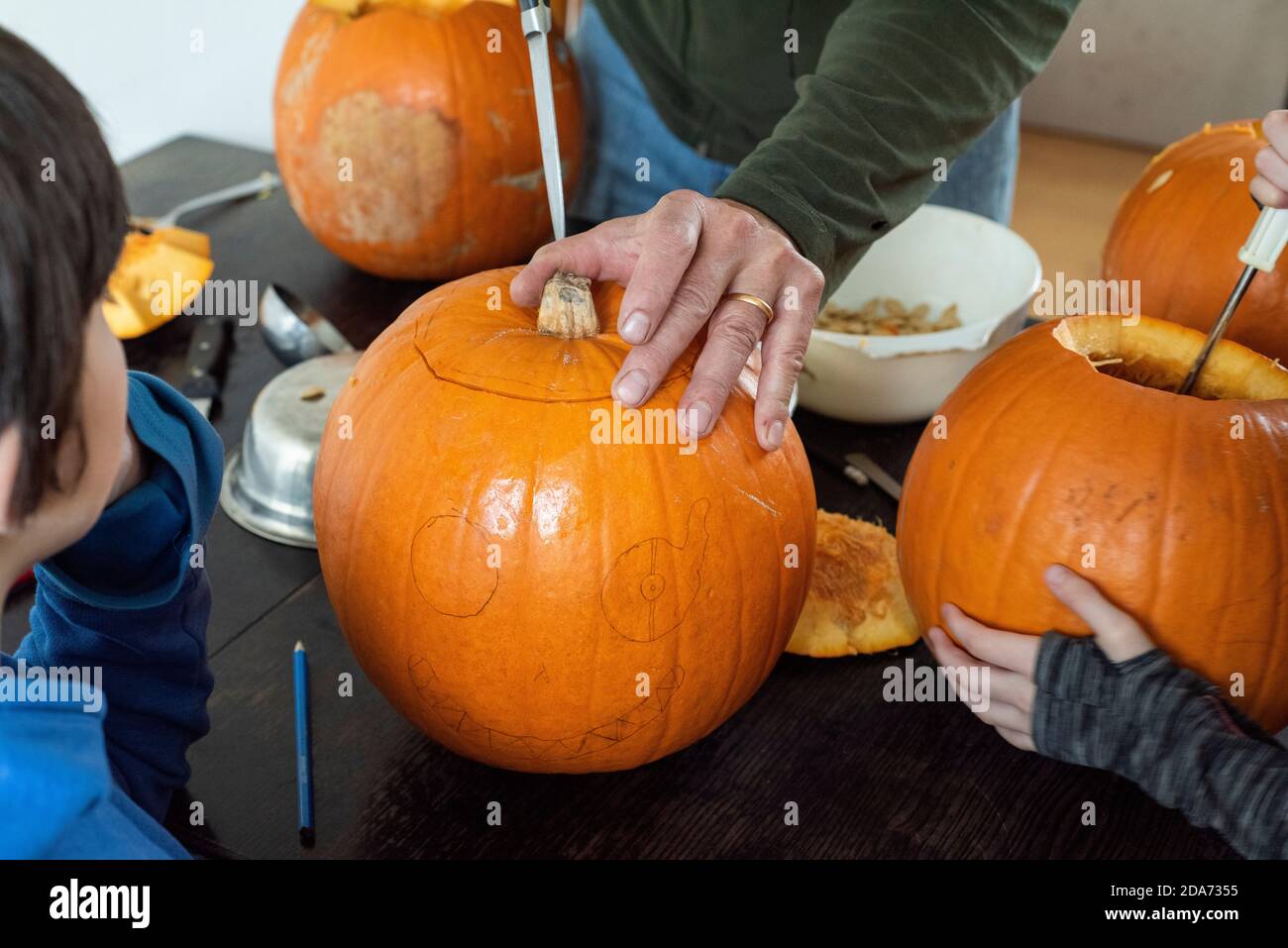 Sheffield UK –  October 30 2019 : Halloween preparations as dad and the children get busy carving the Jack O Lanterns Stock Photo