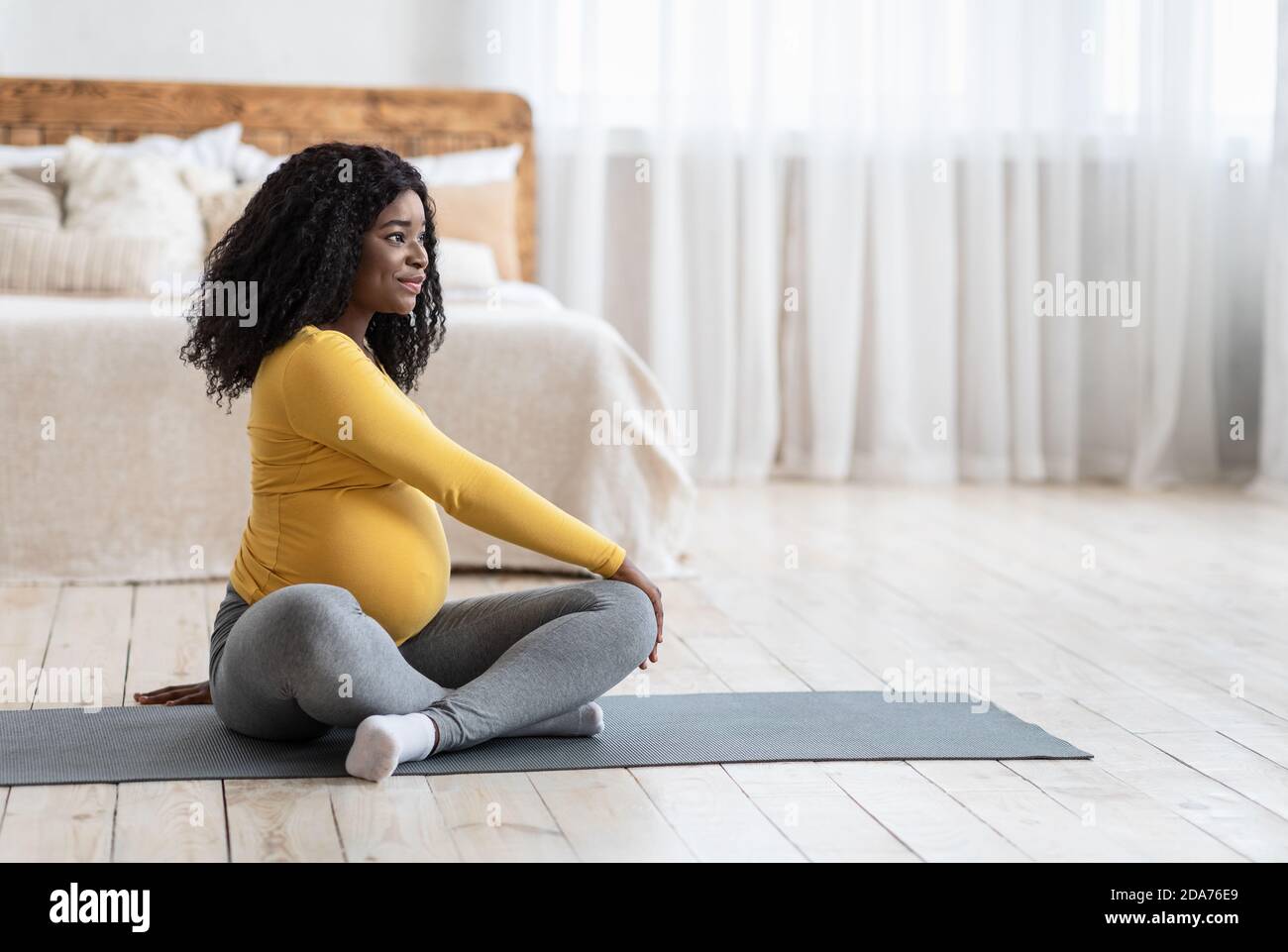 Sporty black pregnant woman sitting on yoga mat, exercising Stock Photo ...