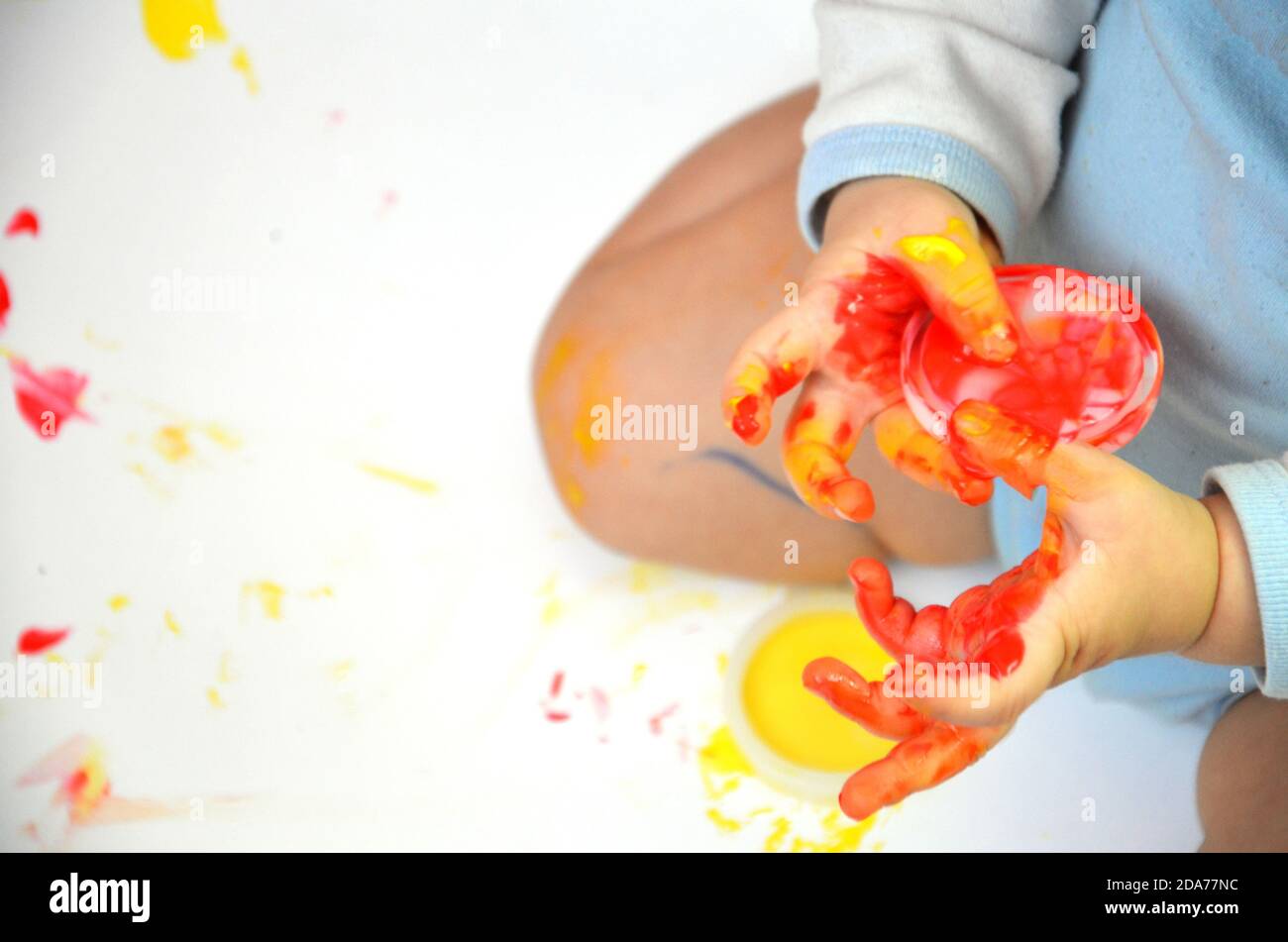 happy baby child draws with colored paints hands, fingers and palms are ...
