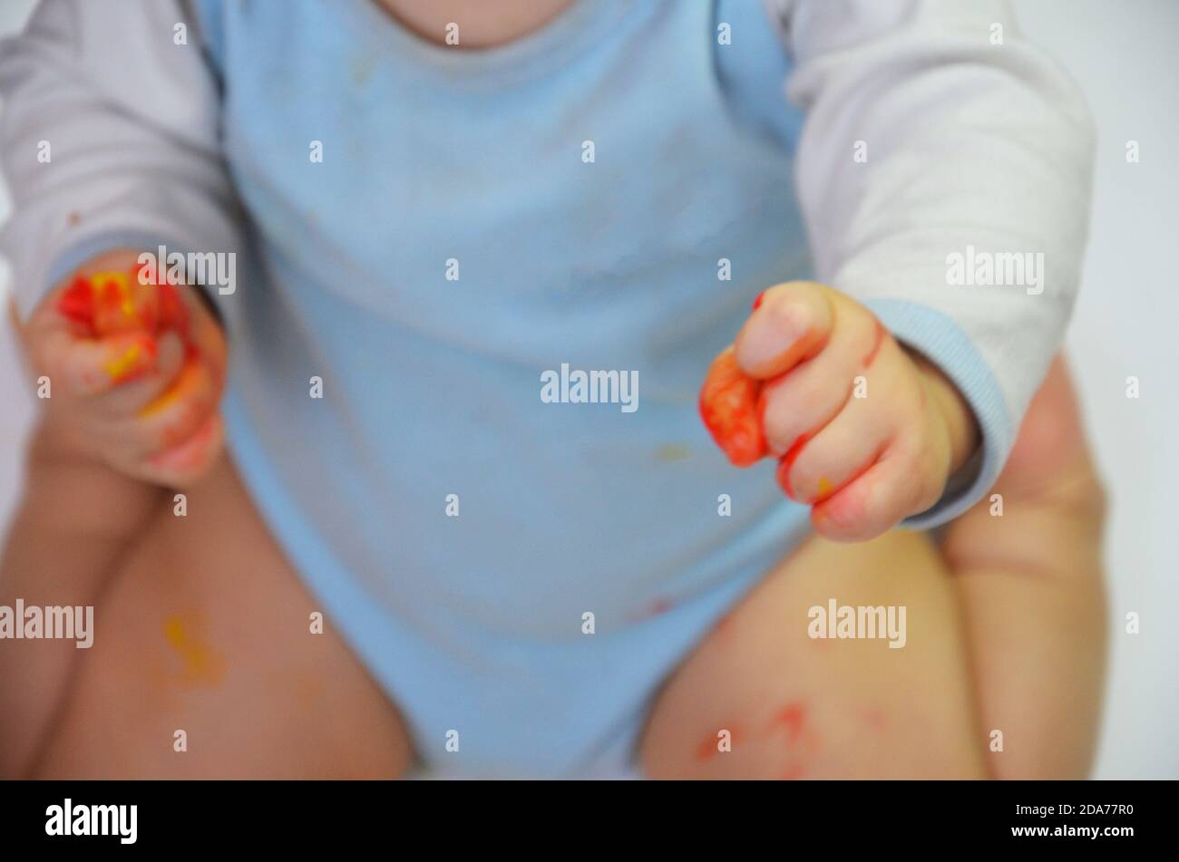 happy baby child draws with colored paints hands, fingers and palms are ...