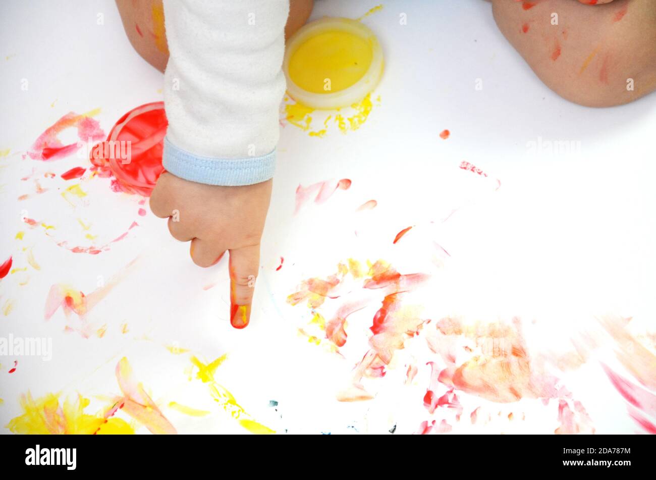 happy baby child draws with colored paints hands, fingers and palms are ...