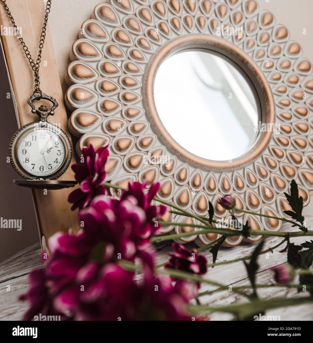 old round vintage clock on a chain next to a round mirror in the interior Stock Photo