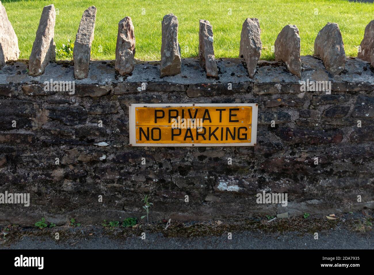 a close up view of a private no parking sign that has been attached on a stone wall outside a private residence Stock Photo