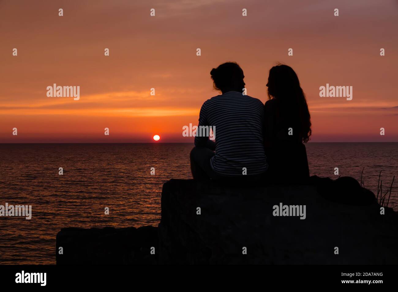 Romantic scene. Silhouette of a young couple in love on the background of  sea sunset Stock Photo - Alamy