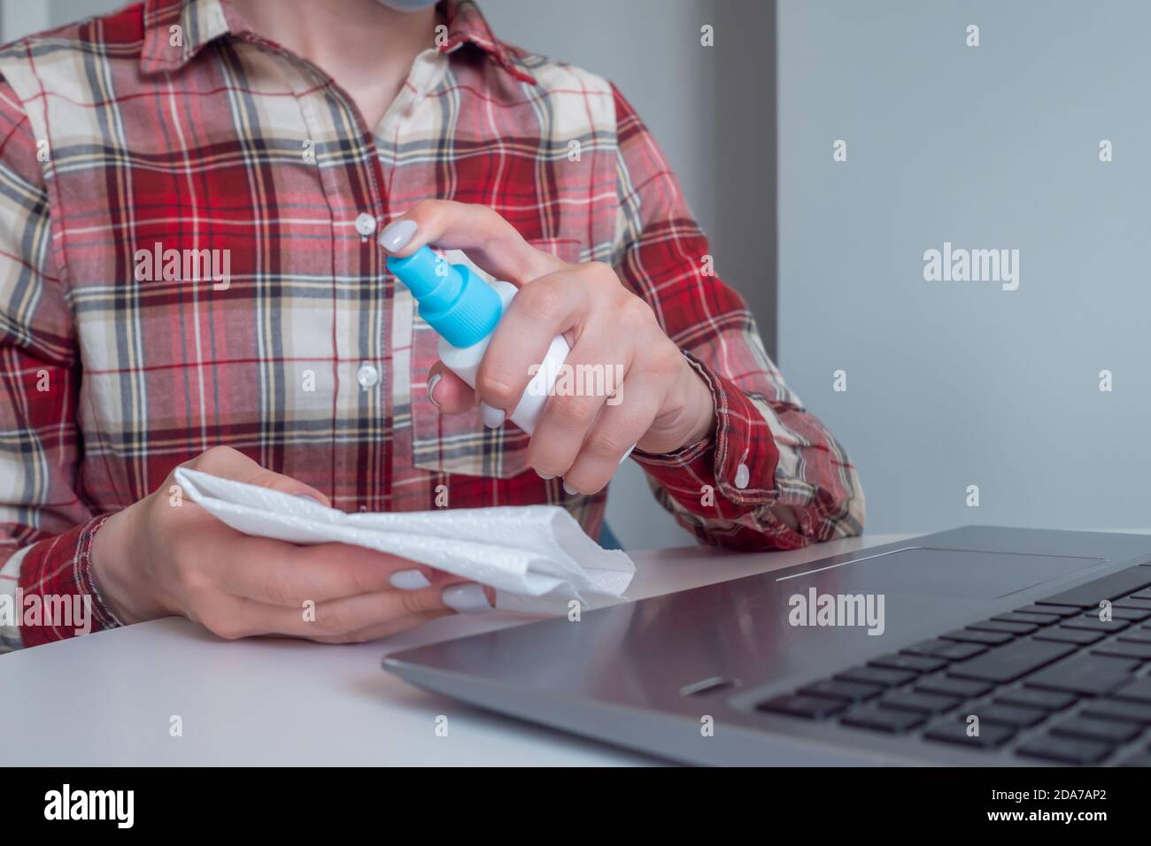 Woman hands spraying antiseptic, cleaning laptop keyboard with