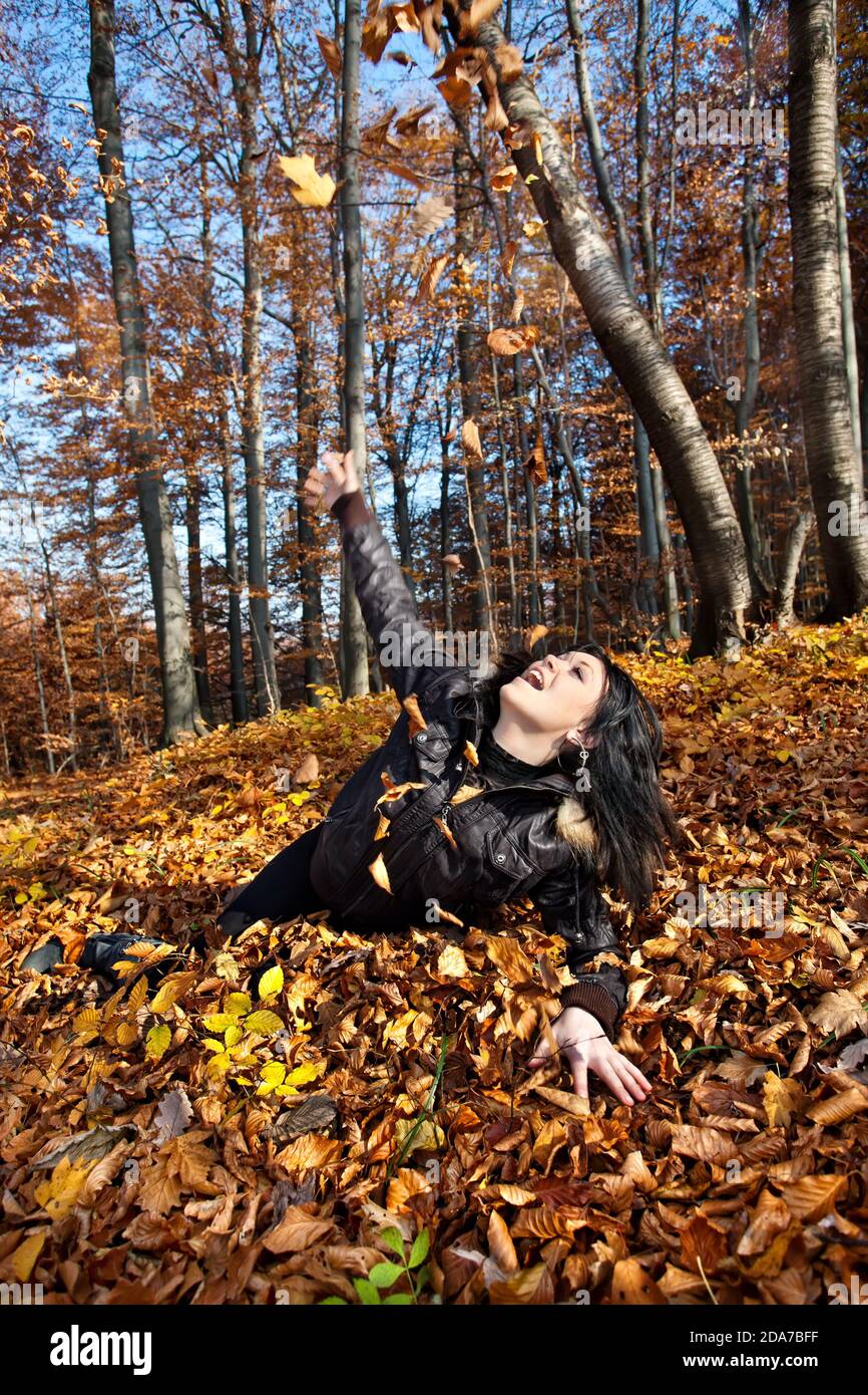 Young woman lying in fallen autumn leaves Stock Photo - Alamy