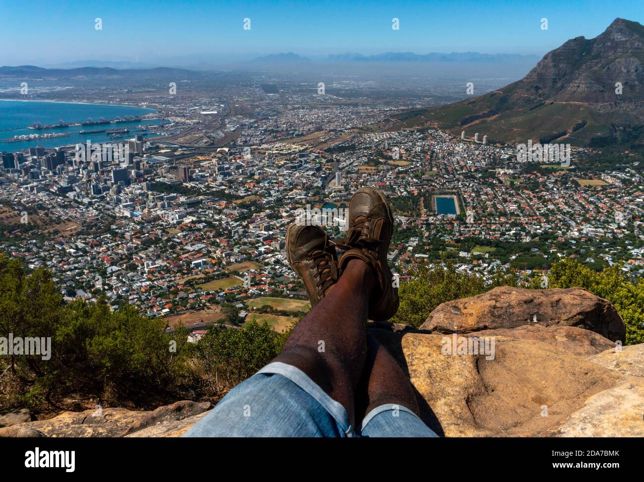 POV of a young hiker Afro American man sitting enjoying a beautiful view of Cape Town from the top of Lion's Head mountain.hiker relaxing Stock Photo