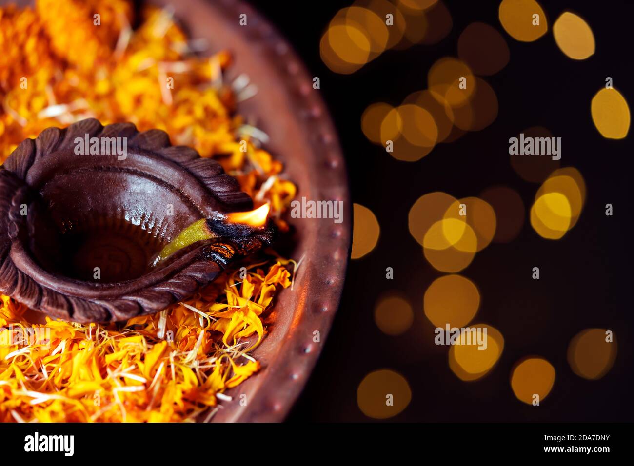 Happy Diwali - Diya oil clay lamp beautifully decorated with orange flowers on the festive occasion of deepawali. Background for Hindu religious ritua Stock Photo