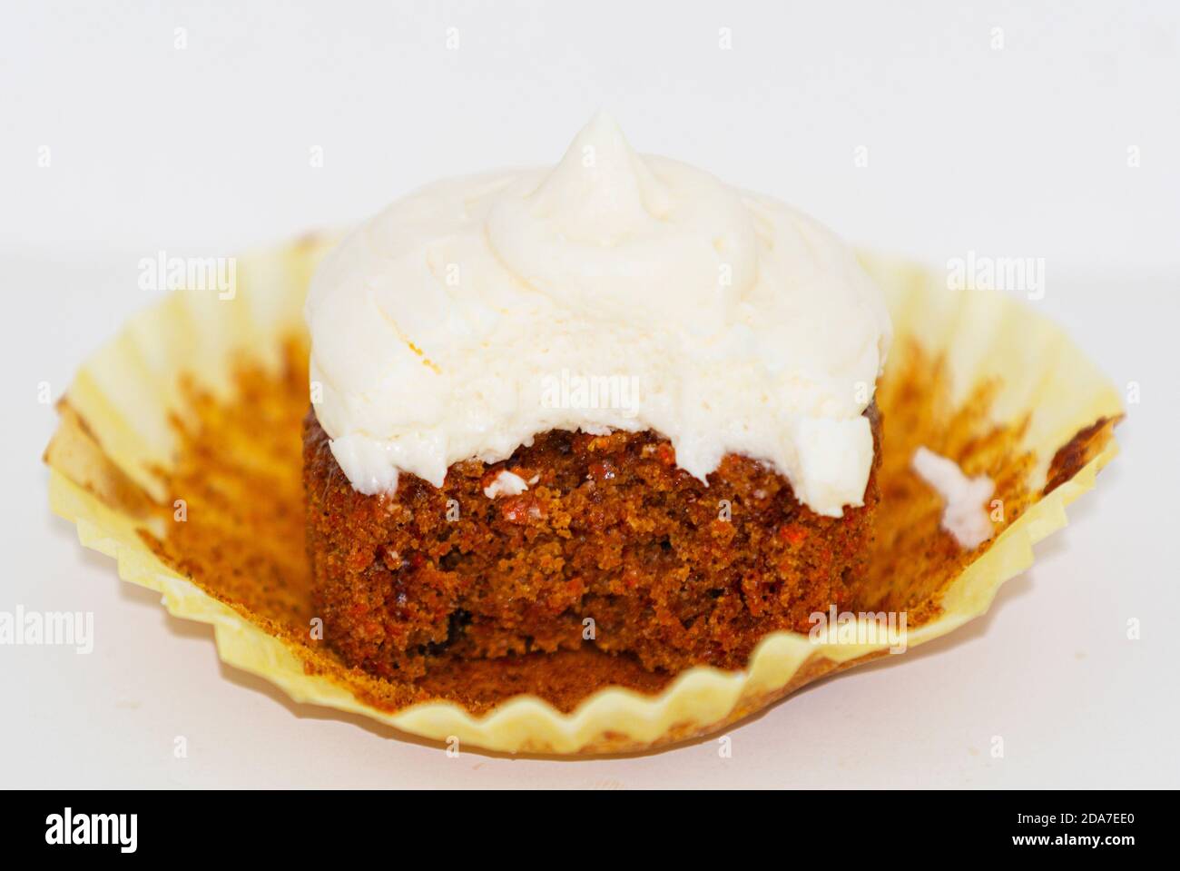 A carrot cake cupcake with cream chees frosting has a bite out of it with a white background Stock Photo