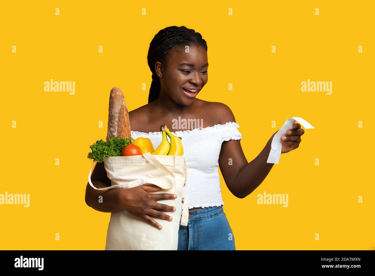 Shopping Economy. Happy Black Woman Holding Bag Of Groceries And Checking Receipt Stock Photo