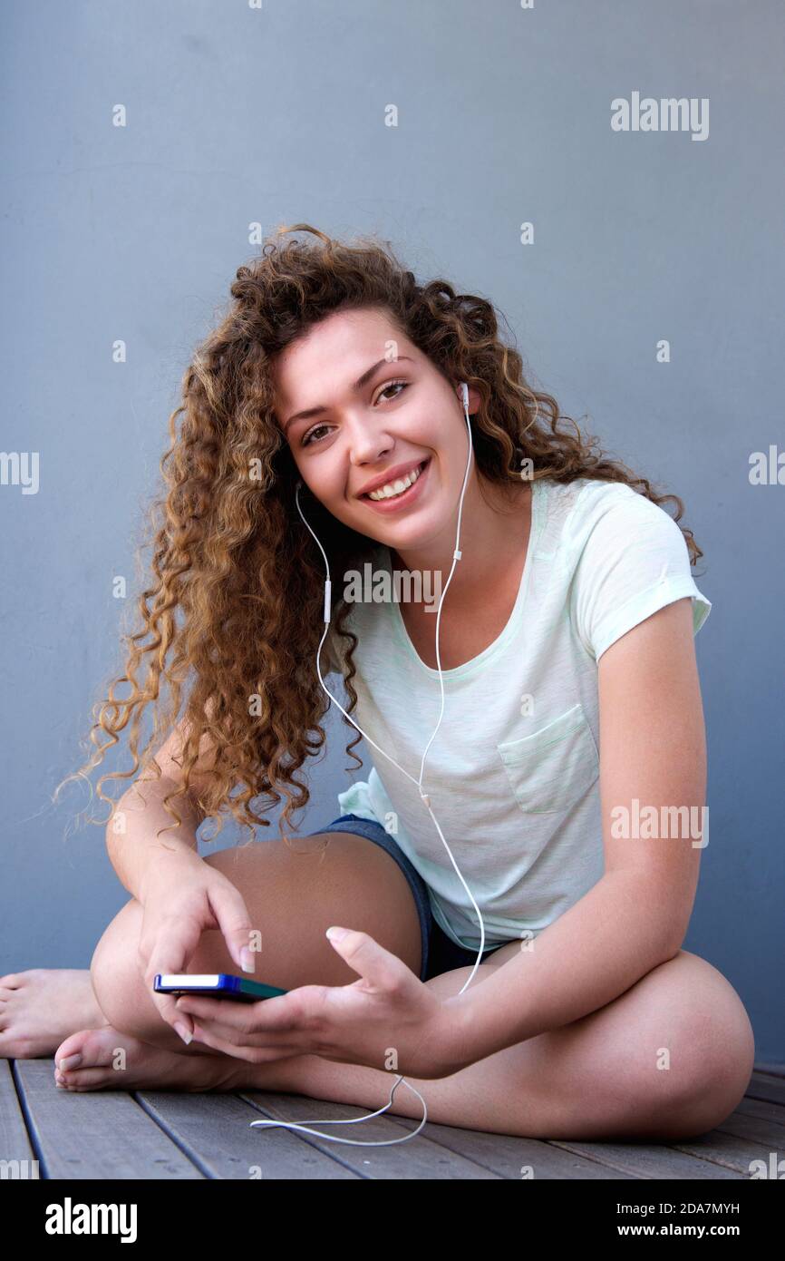 Portrait of happy young girl sitting on floor listening to music Stock ...