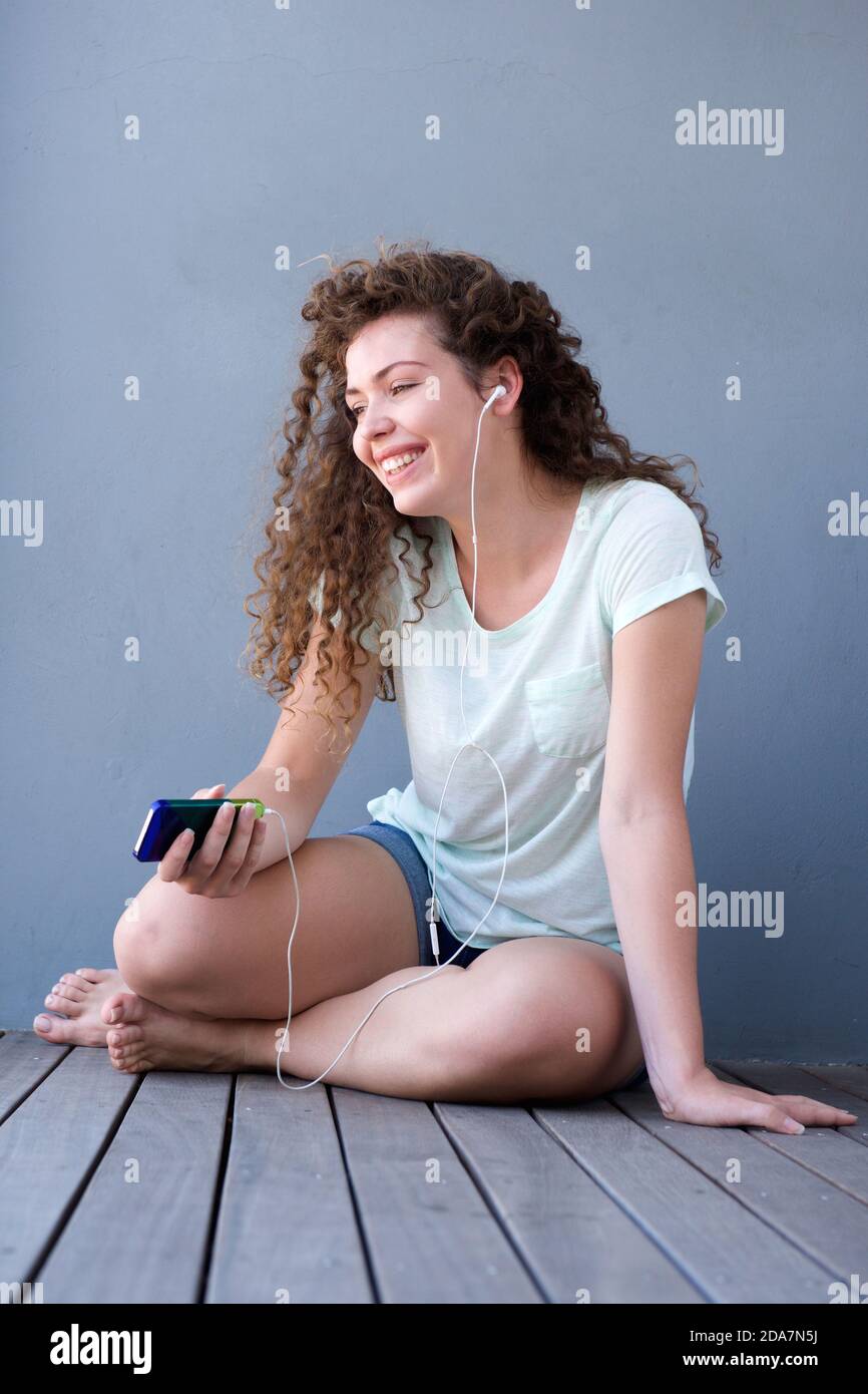 Portrait of happy teen girl sitting on floor listening to music Stock ...