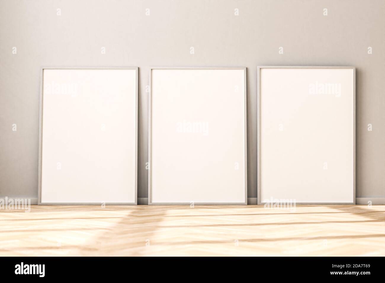 Three empty Picture Frames on parquet floor leaning against bright wall. Sunlight flooding in from the left. 3d render mockup. Stock Photo